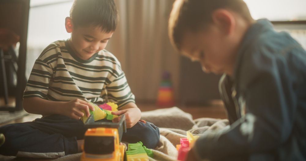 Portrait of Two Male Asian Kids Playing with Colorful Building Blocks in Their Room During the Day.