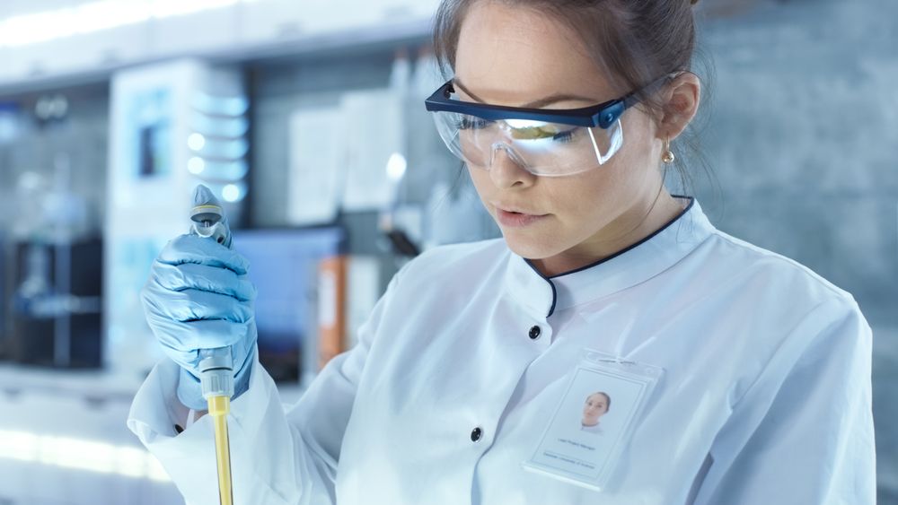 Female Research Scientist Uses Micropipette Filling Test Tubes in a Big Modern Laboratory.