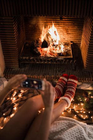 Anonymous woman sitting and taking photo of fireplace