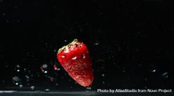 Side view of water on dark background with a floating strawberry 4jJVJ4