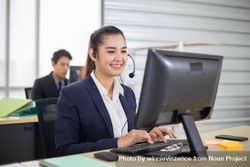 Smiling Asian business call center employees sitting in office 5QeGE5
