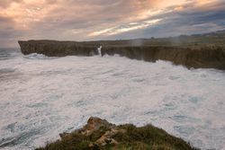 Powerful wave splashing at granite cliff