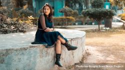 Woman in dress sitting on concrete bench outdoor bEkQ65