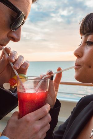 Young man and woman drinking juice from one glass