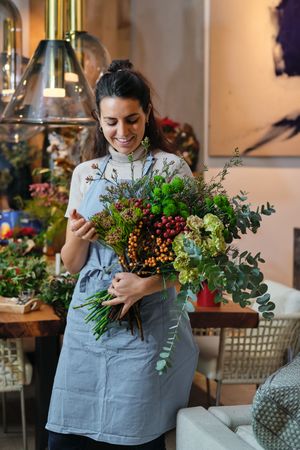 Cheerful woman looking at bouquet in flower shop