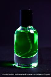 Green perfume bottle in dark studio bGRNZX