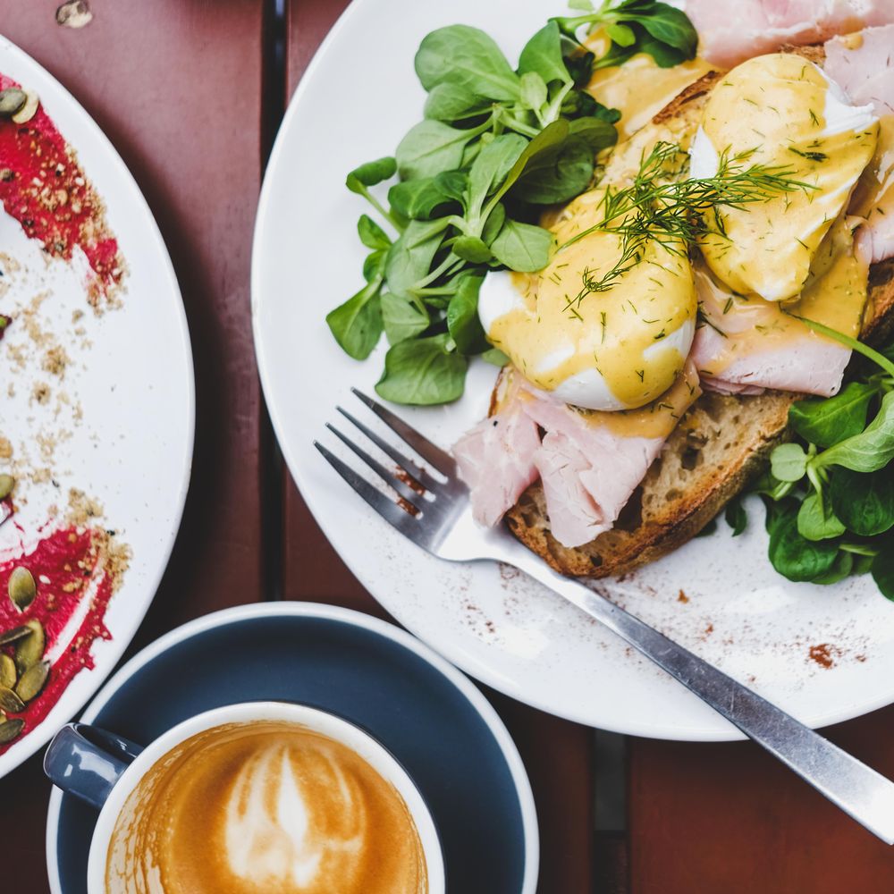 Eggs Benedict with greens, coffee, top view, square crop