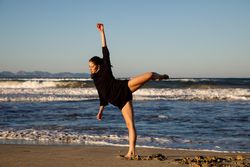 Woman with upped leg near water on shore
