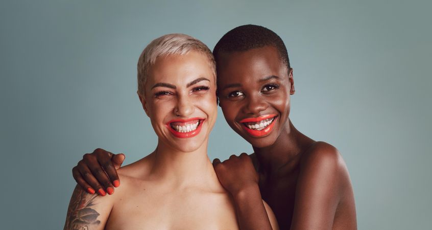 Portrait of two beautiful young women with makeup against a grey background