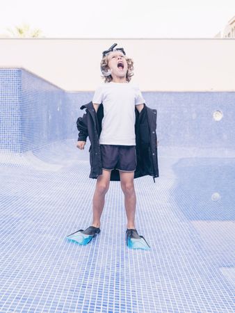 Angry boy in flippers and mask in empty pool