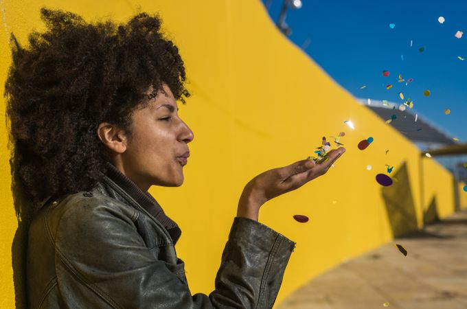 Black woman with afro hair celebrating with confetti.