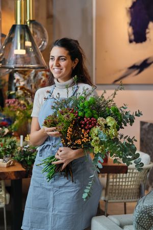 Positive female florist with flower bouquet