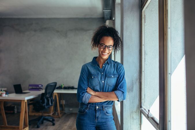Confident entrepreneur standing in office with her arms crossed