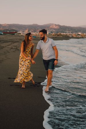 Lovely couple walking holding hands on sandy beach