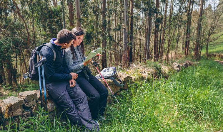 Couple doing trekking sitting looking at a map