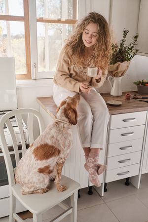 Content woman with dog in kitchen