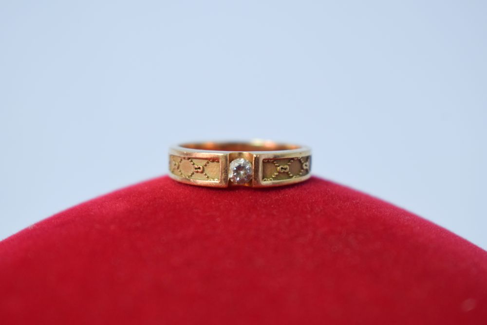 Man's diamond ring resting on red pillow