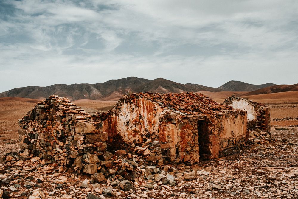 Dilapidated old buildings in mountain desert under cloudy sky