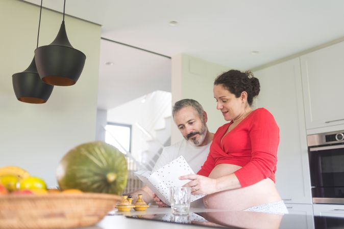 Pregnant woman and male partner reviewing recipe book