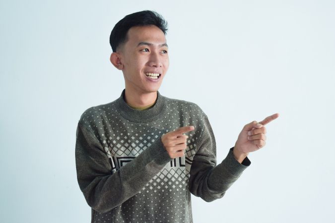 Asian young man pointing to his side and smiling