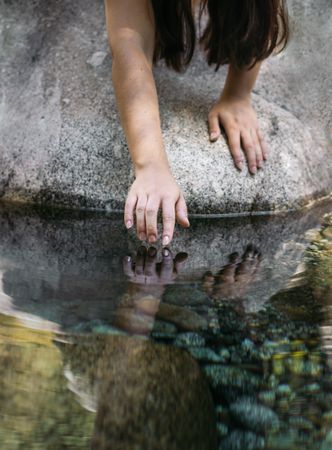 Close up of a hand touching the water of the river