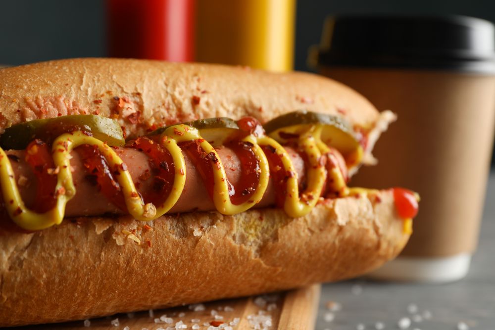 Tasty hot dogs, coffee and sauces on wooden background