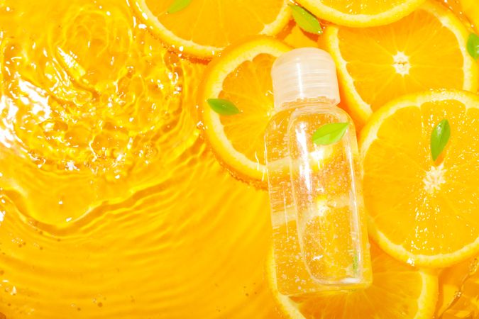 Top view of orange slices with leaves soaking in fresh water with plastic bottle and copy space