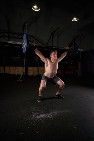 Strong man lifting barbell with weights in gym