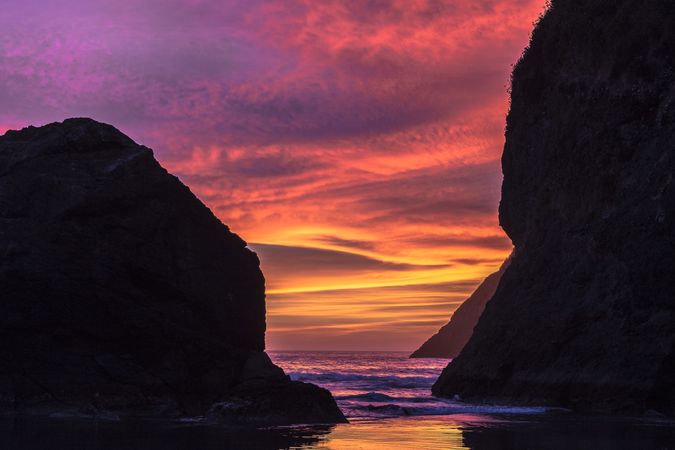 Pink and bright yellow sunset between coastal rocks