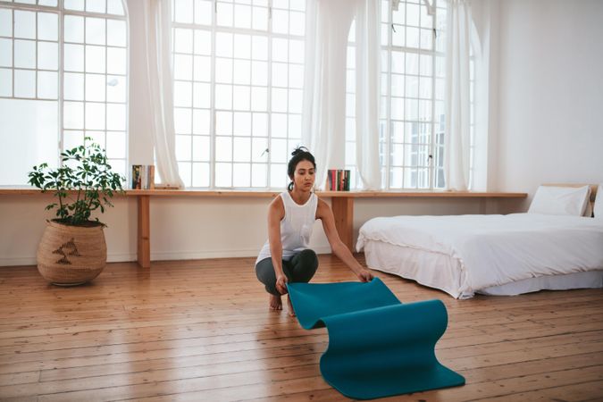 Young woman placing yoga mat down in bedroom