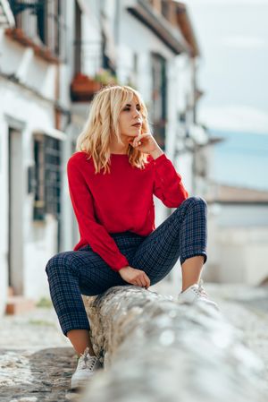 Blonde female with red shirt sitting outdoors, vertical