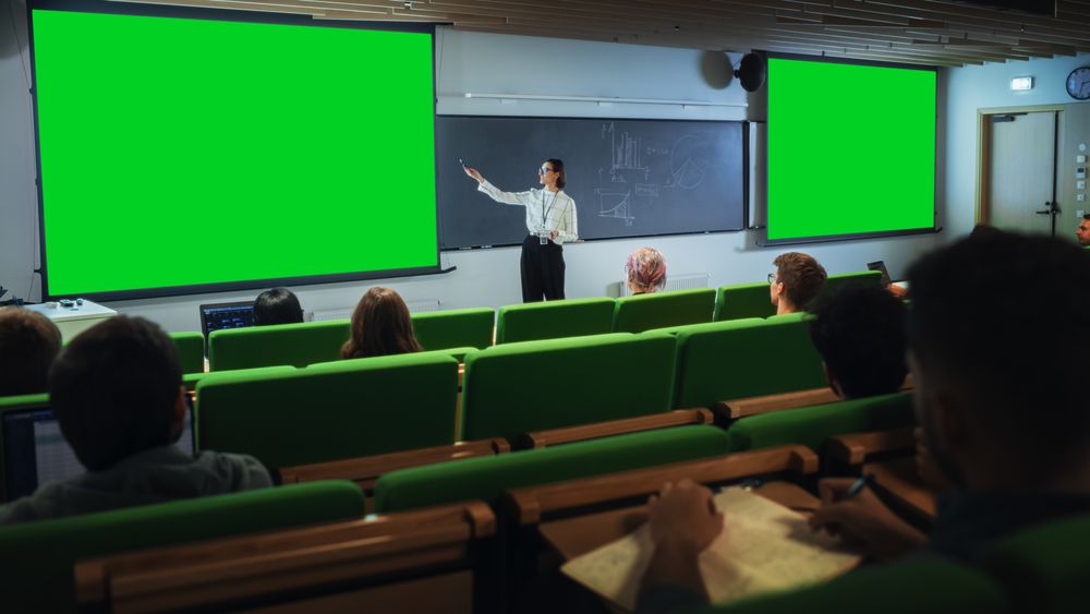 Young Female Teacher Giving a Lecture, Showing Slides on a Green Screen Mock Up Display