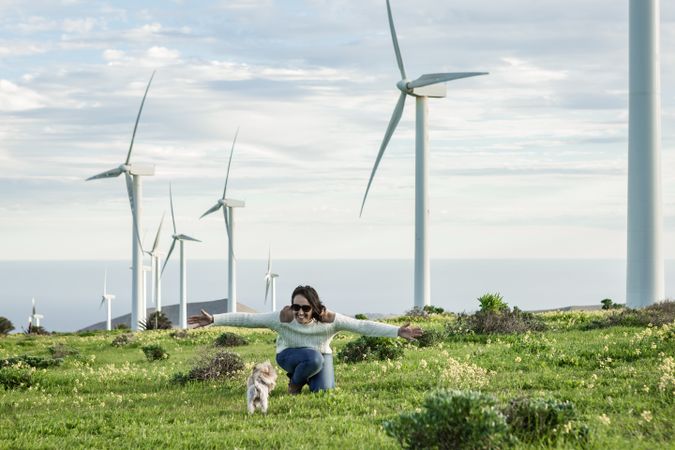 Cheerful woman running on green grass nearby wind turbine farm in Lanzarote, Spain