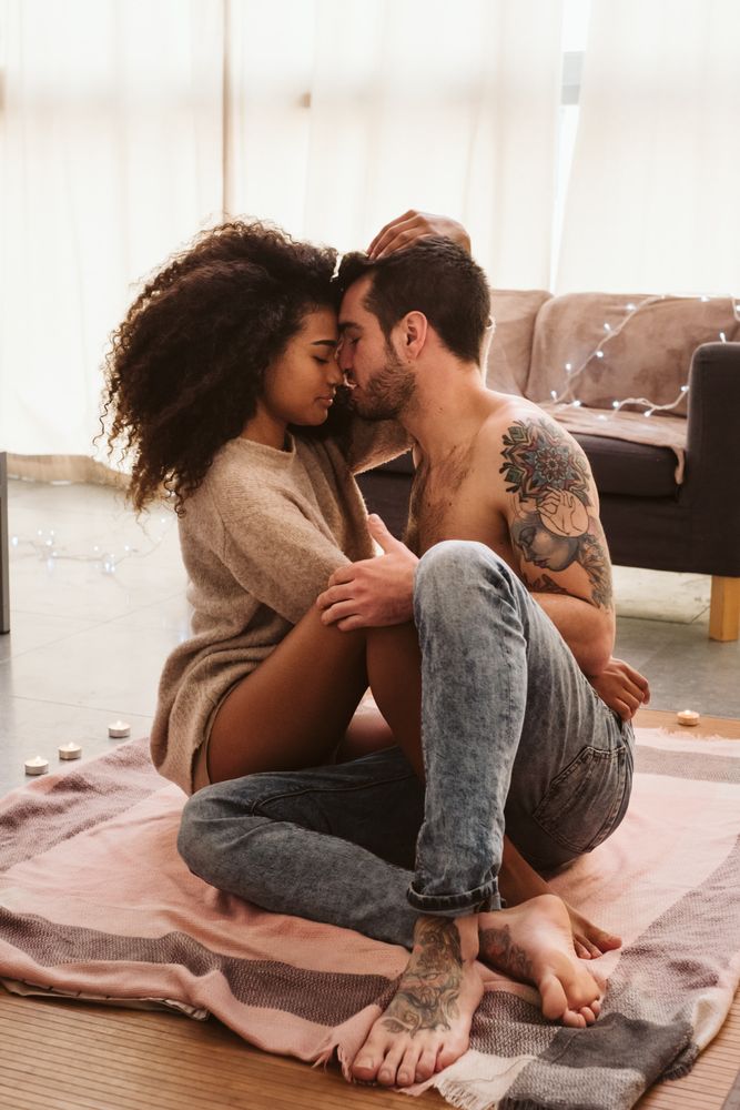 Multiethnic couple hugging on floor at home
