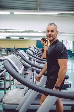 Portrait of fit man doing cardio on treadmills in gym