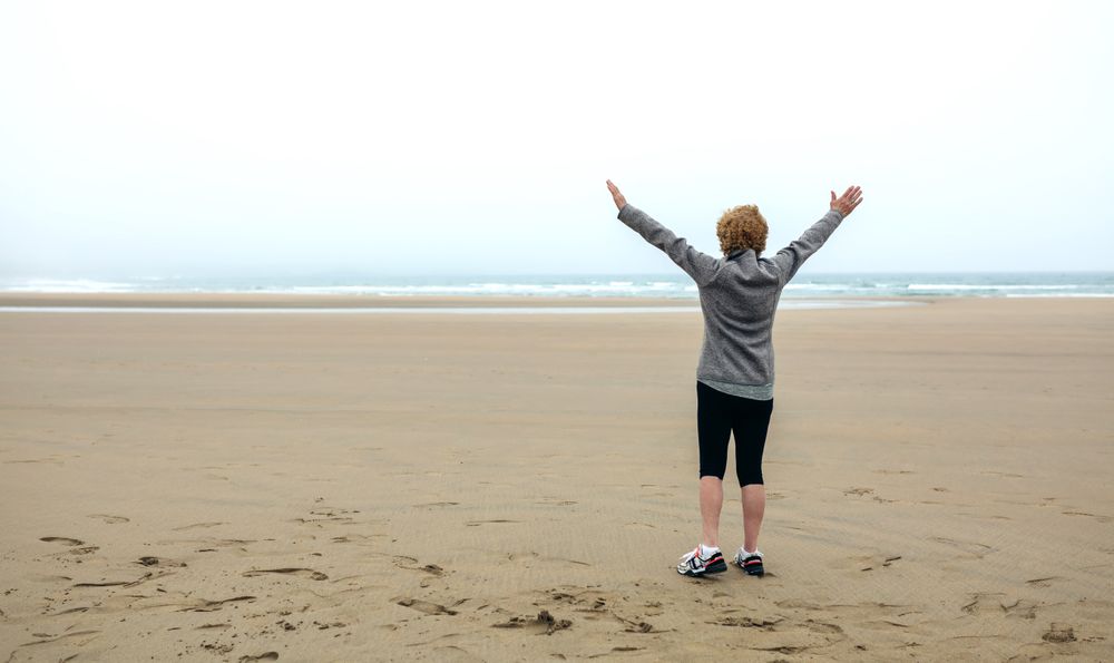 Woman watching the sea with hands up
