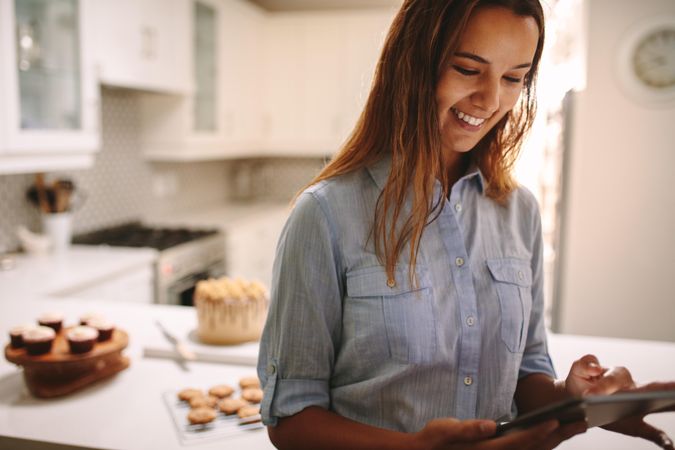Happy baker using digital tablet in kitchen