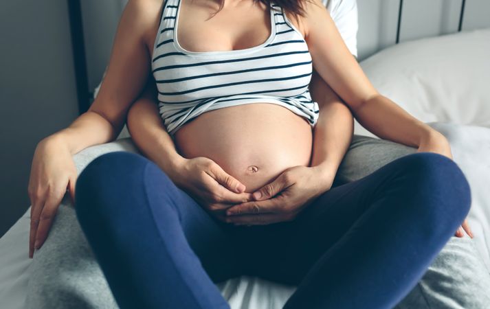 Pregnant woman embraced by her husband