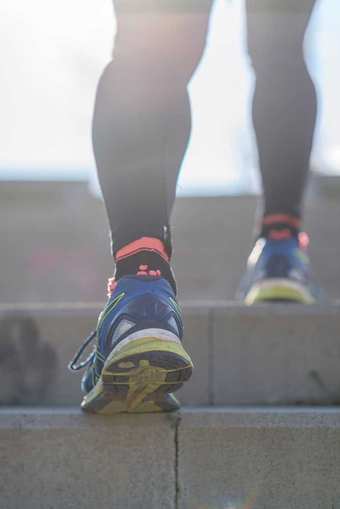 Blue and yellow trainers of fit person walking up stairs