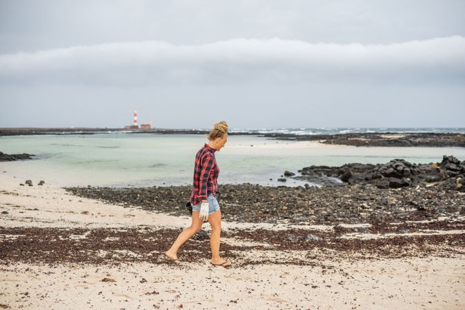 Content modern woman picking litter from sandy seashore