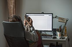Woman rubbing cat's head while working on computer