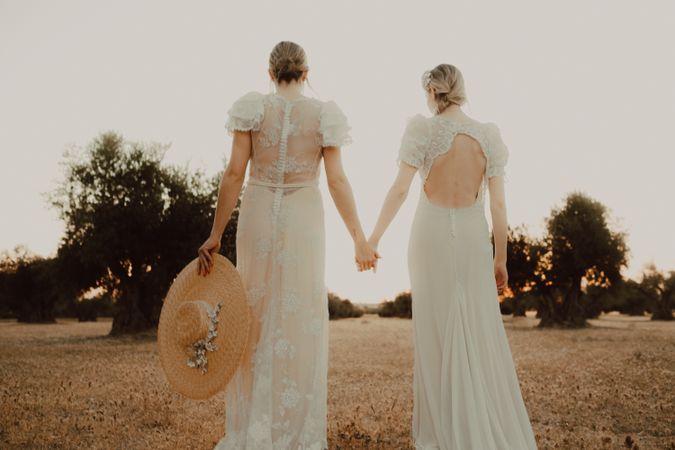 Slim brides in lace dresses holding hands