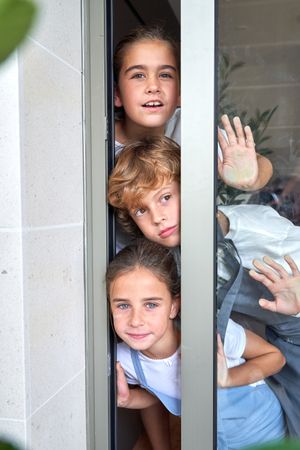 Cute kids peeking near glass door