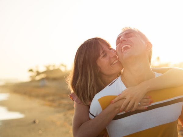 Man carrying woman on back near sea