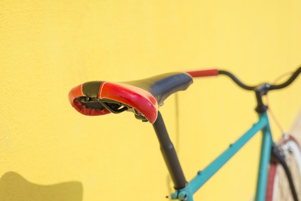 Red seat of bike outside on bright yellow wall