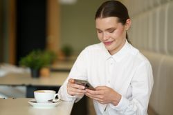 Businesswoman working using mobile enjoying coffee in a chic cafeteria