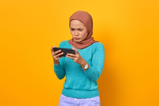 Intense Muslim woman looking at her smartphone