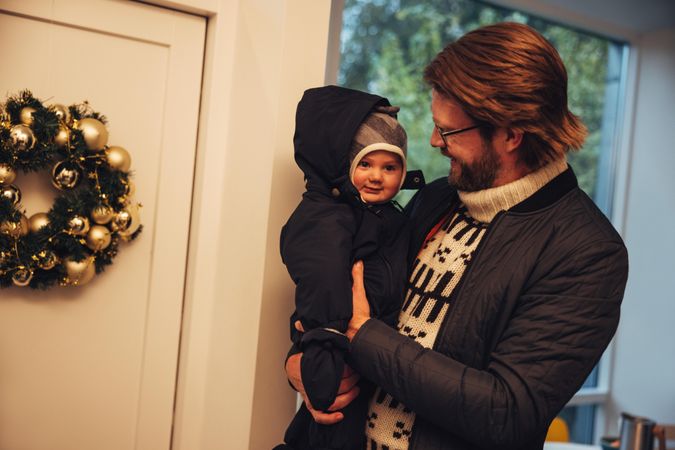 Man with his baby boy in sweaters and coats at home during Christmas