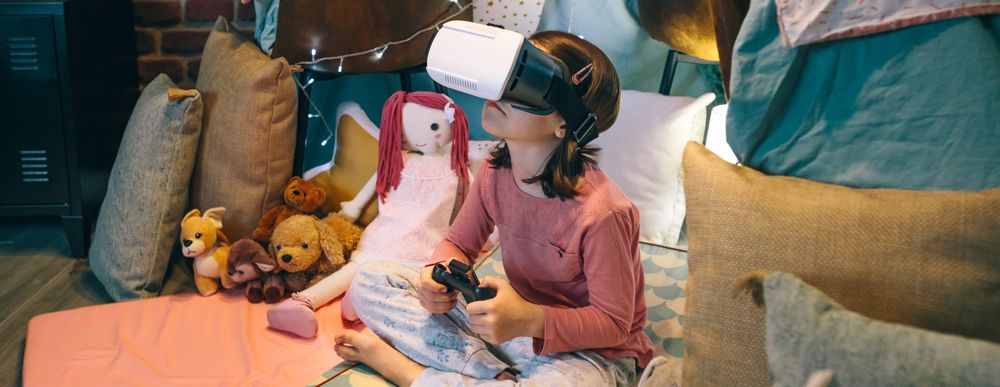 Banner of little girl using virtual reality glasses to study science sitting over mat in tent
