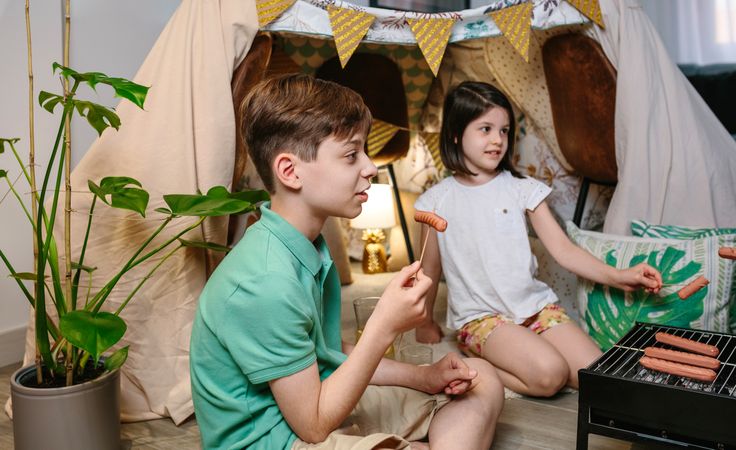 Children grilling and eating sausages on barbecue